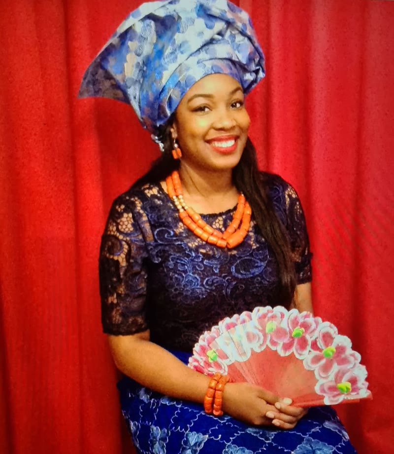 An Ukwuani instructor in traditional dress — blue lace blouse and wrapper, coral beads and a matching gele.